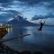 Boy jumping into the sea before a glowing Mayon Volcano